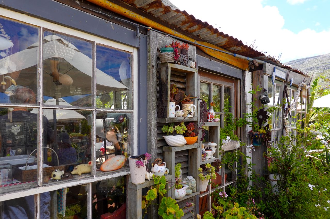 A rustic shed with artistic garden decor and potted plants creating a charming outdoor setting.